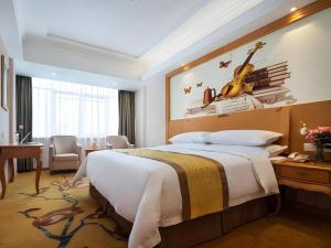 a bedroom with a large bed with a guitar on the wall at Vienna Hotel Guangdong Huidong Herung Pedestrian Street in Huidong