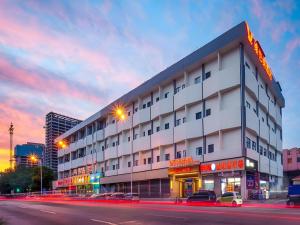 ein großes weißes Gebäude mit davor geparkten Autos in der Unterkunft Vienna Hotel Tianjin Chentangzhuang Metro Station in Tianjin