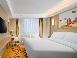 a bedroom with a large white bed and a desk at Vienna Hotel Anhui Huainan Railway Station in Huainan