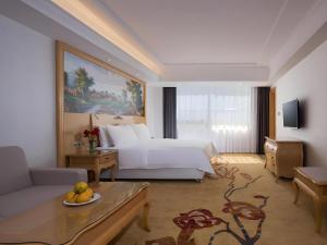 a hotel room with a bed and a couch at Vienna Hotel Guangdong Huizhou Huabianling Square in Huizhou