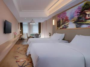 a hotel room with two beds and a painting on the wall at Vienna Hotel Bishan Central Street in Zengjia +90 photos
