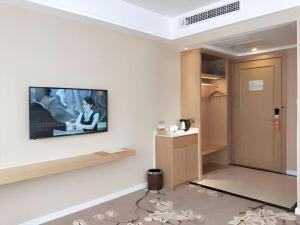 a living room with a tv on a wall at Vienna Hotel Shandong Qingdao Taidong Pijiu Street Liaoning Road in Qingdao