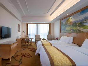 um quarto de hotel com duas camas, uma escrivaninha e uma televisão em Vienna Hotel Guangdong Foshan Lishui 1st City em Lishui