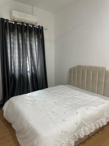 1 dormitorio con cama blanca y cortina negra en Medina Luxe Stay, en Kota Bharu