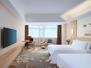 a hotel room with a bed and a flat screen tv at Vienna Hotel Shandong Dezhou Government Shopping Plaza in Dezhou