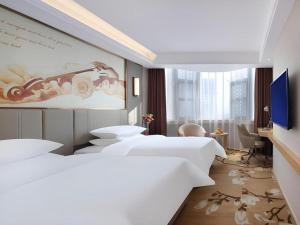 a bedroom with four beds and a painting of a car at Vienna Hotel Shaanxi Xianyang Huitong China Square in Xianyang