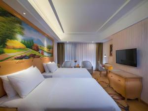 a hotel room with two beds and a flat screen tv at Vienna Hotel Guangdong Meizhou Fengshun in Tangkeng