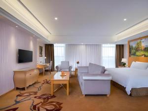a hotel room with a bed and a living room at Vienna Hotel Guangdong Meizhou Fengshun in Tangkeng