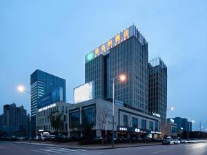 a large building with many windows on a city street at Vienna Hotel Jiangsu Zhangjiagang Passenger Terminal Station in Zhangjiagang