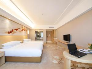 a hotel room with a bed and a laptop on a desk at Vienna Hotel Guangxi Liuzhou Sanjiang Gulou Niaochao Passenger Station in Sanjiang