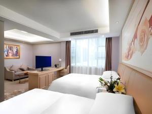 a hotel room with two beds and a television at Vienna Hotel Guangxi Hechi Jinchengjiang Baima Street in Hechi +133 photos