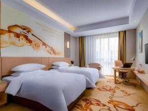 a hotel room with three beds and a painting on the wall at Vienna Hotel Anhui Fuyang Funan Bailing Apartment in Funan