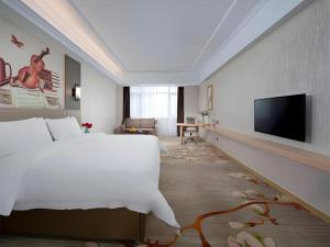 a bedroom with a white bed and a flat screen tv at Vienna Hotel Anhui Taihe Baitai Xingma International in Taihe