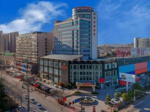 a tall building in a city with a street at Vienna Hotel Shandong Zaozhuang Qingtan Road in Zaozhuang
