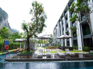 Una piscina con sillas y sombrillas al lado de un edificio. en B2 Krabi Ao Nang Premier Resort, en Ao Nang 