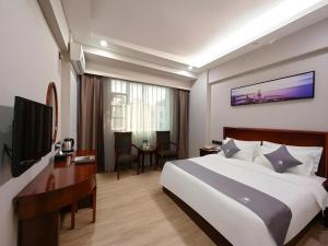 a hotel room with a large bed and a television at Green Tree Inn Zhuhai International Airport Huafa Shangdu in Zhuhai
