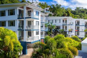 an apartment building with blue balconies and palm trees at Airlie Summit Apartments in Airlie Beach