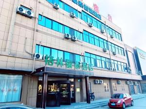 un bâtiment avec une voiture garée devant dans l'établissement GreenTree Inn Express Jinan Zhangqiu Districty Ancinet Town Longquan Road, à Zhangqiu