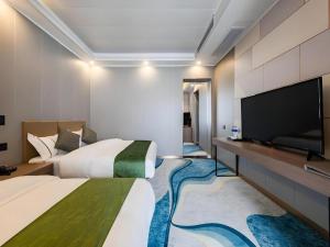 a hotel room with two beds and a flat screen tv at GELI Kunming North Railway Station Zoo in Kunming +16 photos