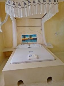 Cama en habitación con marco de cama blanco en palm villa, en Watamu