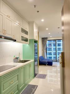 a kitchen with green cabinets and a living room at 2 phòng ngủ master cách Vincom Mega Mall 50m khu GH2 in Long Bình
