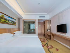 a hotel room with a large bed and a flat screen tv at Vienna Hotel Guangzhou Baiyun Airport Huadu Avenue in Huadu