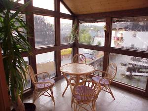 a table and chairs in a room with windows at Pension Löffler in Steinbach am Wald