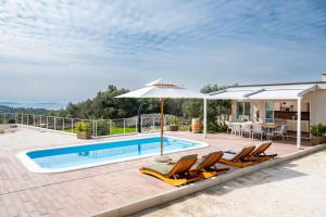 a pool with chairs and an umbrella next to a house at Skriveni dragulj - A Peaceful Oasis with a Sea View in Trogir