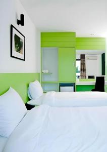 a bedroom with two white beds and a green wall at Siamgrand Hotel in Nakhon Phanom