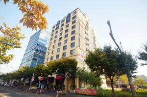 a tall building on a city street with trees at BENIKEA Technovalley Hotel in Daejeon