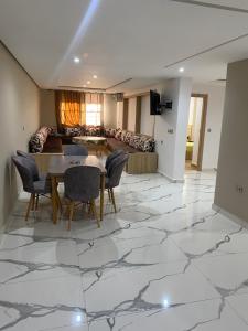 a living room with a table and chairs on a marble floor at Abc Appart in Saidia 