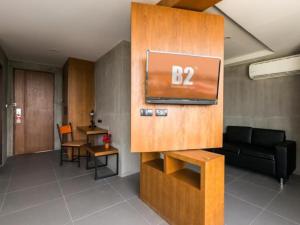 ein Wohnzimmer mit einem Sofa und einem Fernseher an der Wand in der Unterkunft B2 Khon Kaen Boutique & Budget Hotel in Khon Kaen
