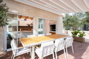 a kitchen and dining room with a wooden table and white chairs at Skriveni dragulj - A Peaceful Oasis with a Sea View in Trogir