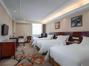 a hotel room with a row of white beds at Vienna Hotel Hangzhou Binkang Road Metro Station in Hangzhou