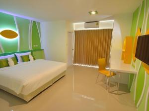 ein Schlafzimmer mit einem Bett und einem Schreibtisch mit Stuhl in der Unterkunft The Rice Hotel in Roi Et