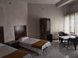 a hotel room with two beds and a table and a window at Collection O Aurangabad Central Bus Terminal in Aurangabad