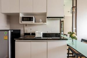 a kitchen with white cabinets and a black refrigerator at Palm Spring Condo Nimman - Deluxe 810 in Chiang Mai
