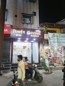 ムンバイにあるDivine Homes AC Dormitoryの店の前でスクーターに乗っている二人