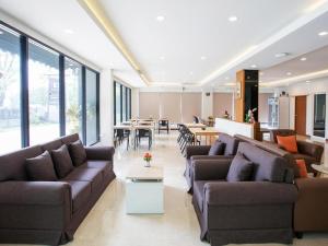 a living room with couches and tables and windows at B2 Sriracha Premier Hotel in Si Racha