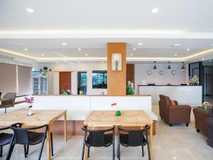 a living room with two wooden tables and chairs at B2 Sriracha Premier Hotel in Si Racha