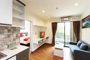 a room with a bed and a living room with a couch at B2 Sriracha Premier Hotel in Si Racha