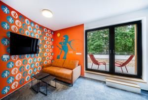 an orange room with a chair and a tv at Hotel Break Hradec Králové in Hradec Králové