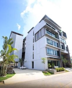 a white building with a car parked in front of it at Luxsna Residence in Hat Yai