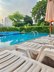 a row of white lounge chairs next to a swimming pool at Hotel Kann Pattaya in Pattaya South
