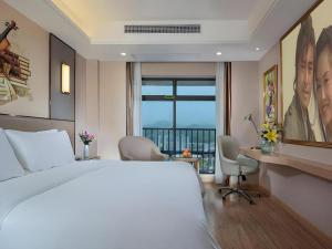 - une chambre avec un lit et un bureau avec des chaises dans l'établissement Vienna Hotel Nanning Xiangsi Lake University Town, à Nanning