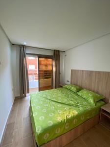 a bedroom with a large bed with a green comforter at Abc Appart in Saidia 