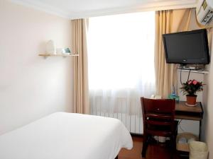 a bedroom with a bed and a desk with a television at GreenTree Inn Urumqi South Xinhua Road Hotel in Ürümqi +178 photos