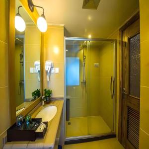 a yellow bathroom with a sink and a shower at Hohhot Shanghua Boutique Hotel in Hohhot