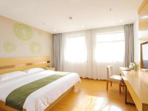 a bedroom with a large bed and a desk with a television at GreenTree Inn Jiaxin Puyuan Kaixuan Road in Puyuan +199 photos