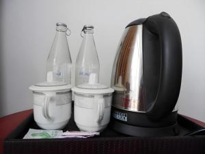 a coffee maker with bottles and a coffee pot at Xishuangbanna Hotel Managed by Xandria Hotel in Ban Nongkham
